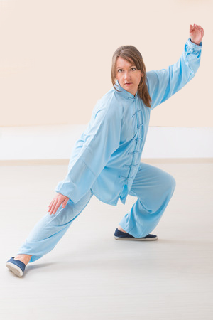 31946188 - beautiful woman doing qi gong tai chi exercise wearing professinal, oryginal chinese clothes at gym